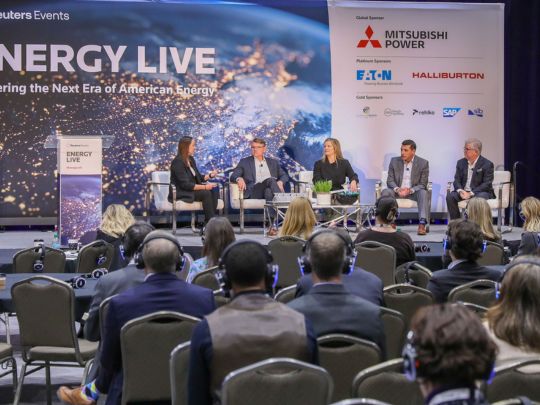 A five-person panel discussion on the main stage at Energy LIVE, with a large audience seated before a banner reading 'Powering the Next Era of American Energy.