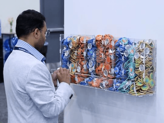 An attendee at a Reuters Events conference standing at the 'Pin Your Passion' interactive networking station, carefully selecting pins to represent his professional interests, illustrating the personalized approach to connecting with peers.
