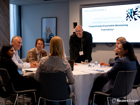 An intimate workshop session at The Future of Insurance event, featuring an interactive discussion on a presentation screen asking, How can Insurers ensure that Embedded Insurance Products are Competitively Priced while Maintaining Profitability?