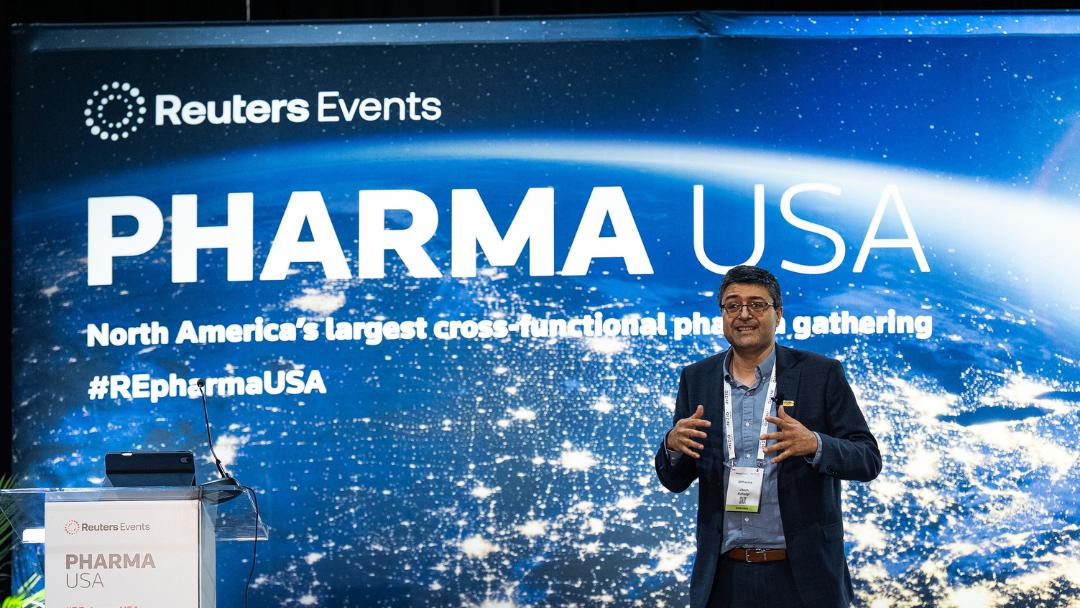 Male executive speaker delivering a keynote on stage next to a podium at Reuters Events Pharma USA 2026