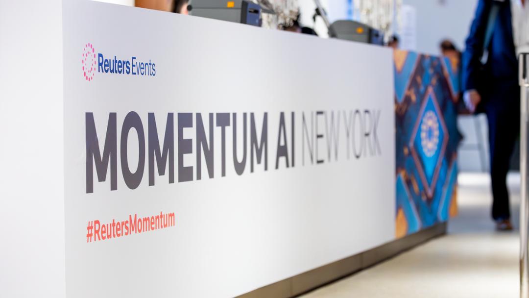 large wall signage in a lobby displaying the event logo for Reuters Events Momentum AI New York 2026