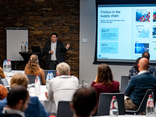 A Supply Chain Europe speaker presents supply chain data and visuals on large screens to an audience.