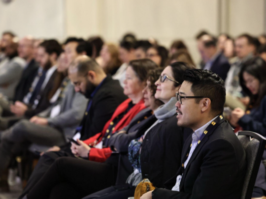 A diverse audience of insurance industry professionals seated and attentively listening during a keynote session at an insurance conference.