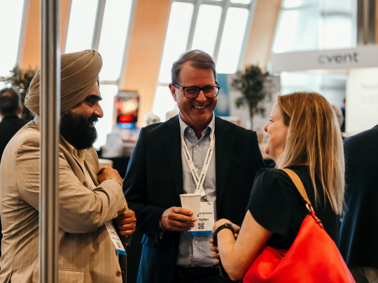 Conference attendees wearing event badges talk and smile during a networking session