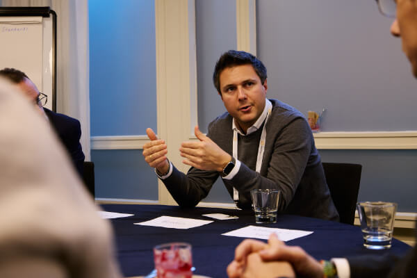 A delegate gesturing while leading a small group roundtable discussion at Sustainability Europe.