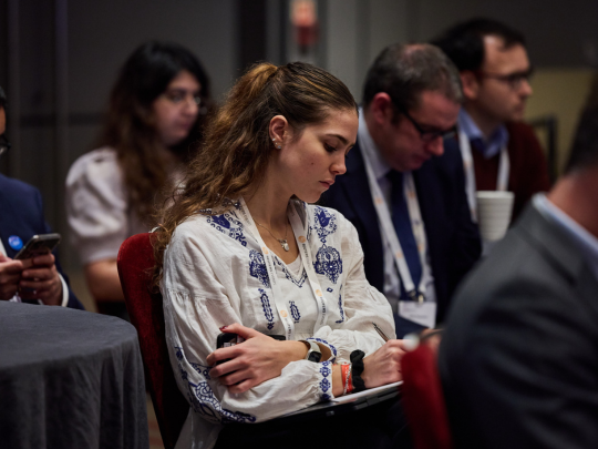 Conference attendee taking notes during an Energy Transition Europe session, with other delegates seated behind her.