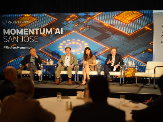 Four panelists seated on stage during a Momentum AI San Jose discussion, viewed from the audience.