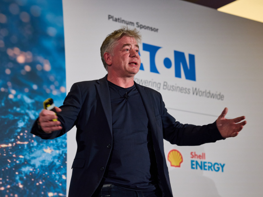 Speaker presenting on stage at Energy Transition Europe, with Eaton and Shell Energy sponsor logos behind him.