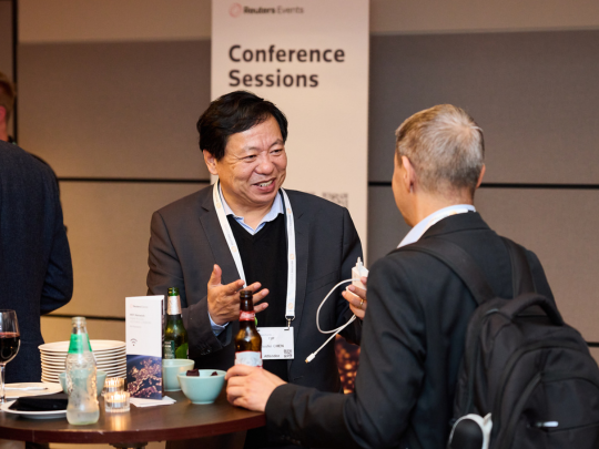 Two delegates talking at a table during networking near the Energy Transition Europe conference sessions area.