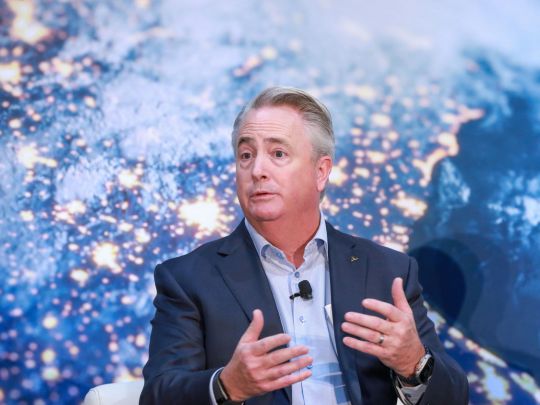A speaker gestures while addressing the audience at Energy LIVE, set against a large illuminated globe backdrop.