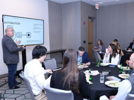 A facilitator presents an automation workflow to attendees during a small-group roundtable discussion at Momentum AI Austin.