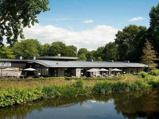 The Rosarium venue beside a landscaped garden and pond in Amsterdam's Amstelpark, set up with outdoor terrace seating.