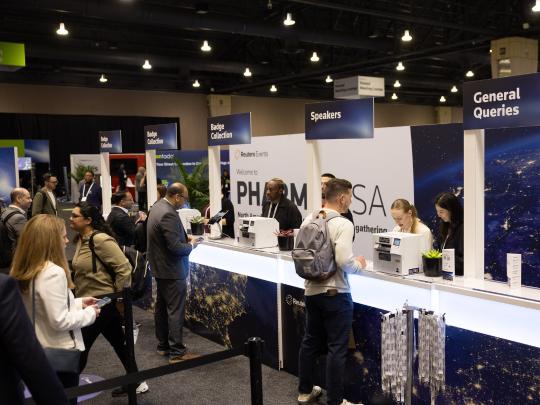 Executives queuing to sign in at a registration desk with staff processing passes at Reuters Events Pharma USA 2026