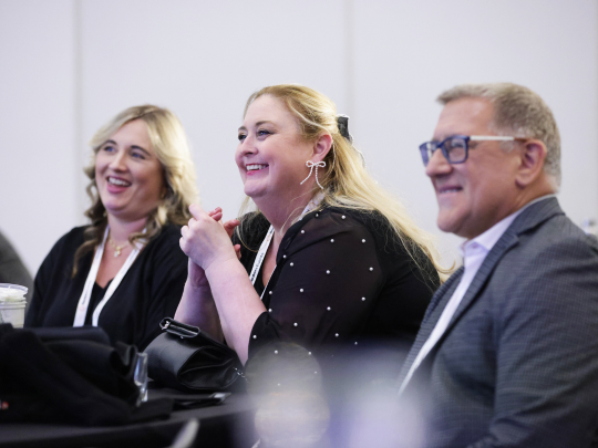 Three attendees listen and smile during a Total Health conference session.
