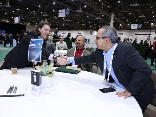 Two attendees shake hands and smile at a numbered roundtable during a networking session at Energy LIVE.
