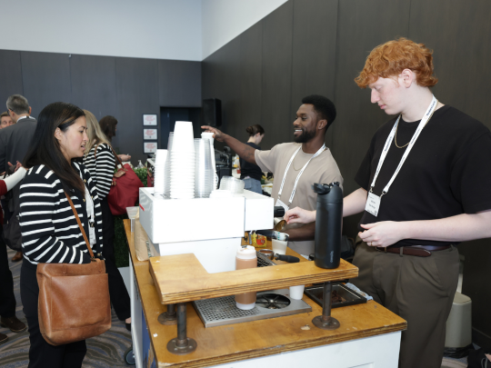 Attendees collect coffee from a barista station during a Total Health conference break.