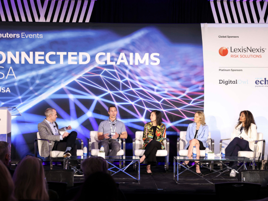 Five industry experts engaged in a panel discussion on the Connected Claims USA main stage, with sponsor branding visible.