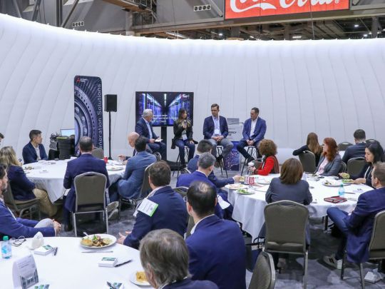 A four-person panel discussion takes place on a small stage during an interactive workshop at Energy LIVE, with attendees seated at round tables in a dome-shaped venue.