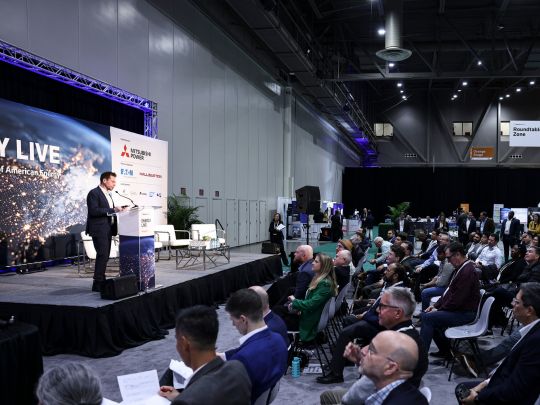 A presenter pitches on stage during the Energy LIVE Shark Tank session, with a seated audience watching under an 'Energy LIVE: Powering the Next Era of American Energy' banner