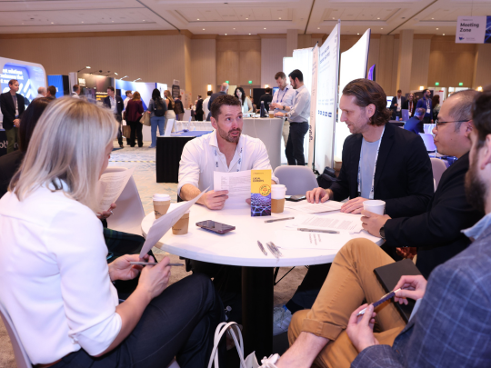Connected Claims USA attendees discuss ideas around a table in the event networking area.