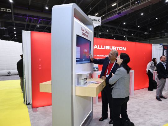 Attendees engage with an interactive 'Low Carbon Solutions' kiosk at the Halliburton booth on the Energy LIVE expo floor.