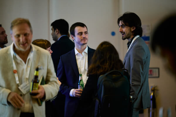Business professionals holding drinks and chatting during an evening social networking reception at Sustainability Europe.
