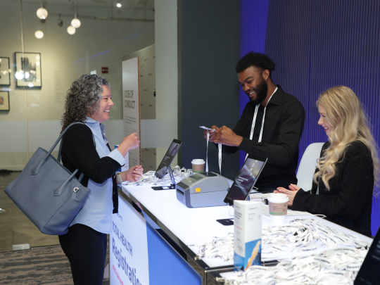 Attendees check in at the Total Health registration desk and receive event lanyards