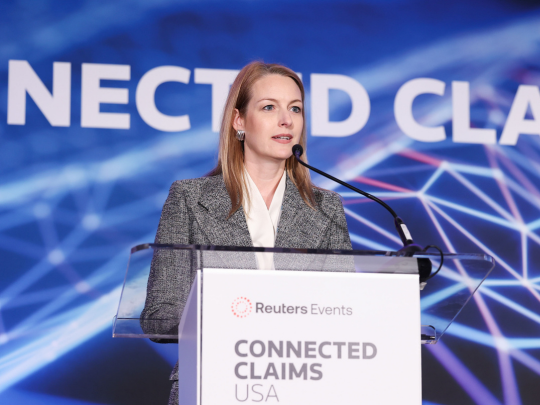 A speaker addresses the audience from the podium at the Reuters Events Connected Claims USA conference.